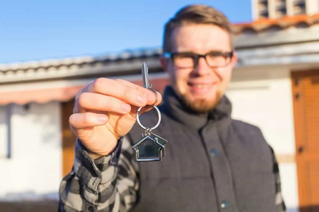 Young happy man showing a house key